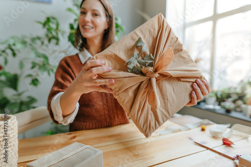 Young woman packing gift box in fabric furoshiki photo