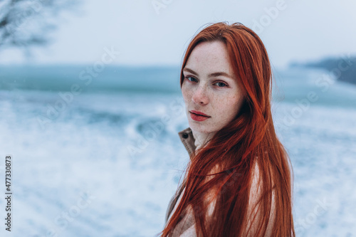 Close up red haired freckled woman portrait outdoor in winter snowy park © Andreshkova Nastya