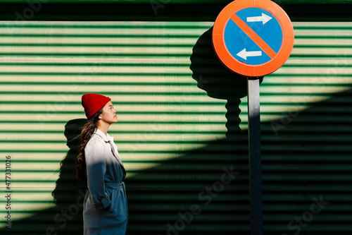 Woman looking at directional sign in front of green wall