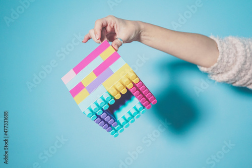 Arm of woman holding colorful cube made of pastel colored toy blocks photo