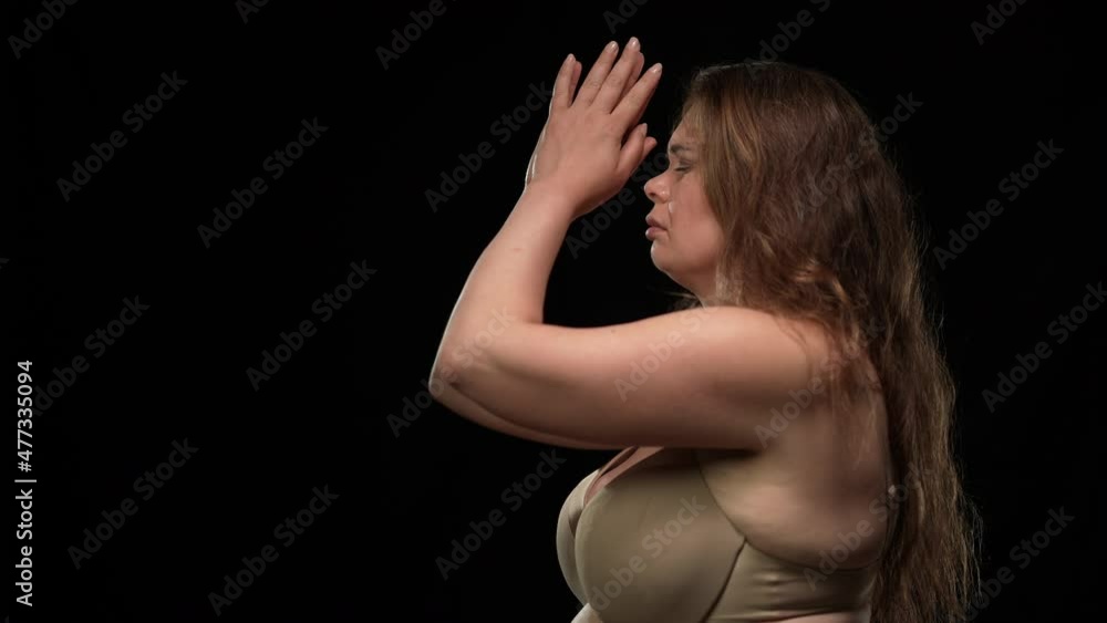 Side view sad obese woman in underwear looking at camera turning away clasping hands praying. Upset unhappy Caucasian plus size lady at black background on the right Side view sad obese woman in underwear looking at camera turning away clasping hands praying. Upset unhappy Caucasian plus size lady at black background on the right