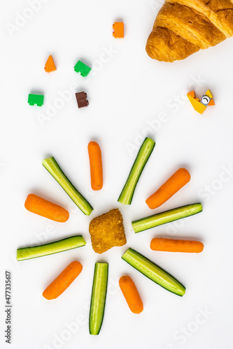 A sun like shape made out of child's health food choices with toy blocks spread through the white background around it
