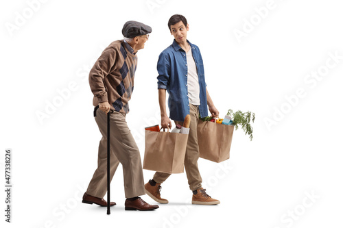 Obraz na plátně Young man carrying grocery bags and walking with a senior man