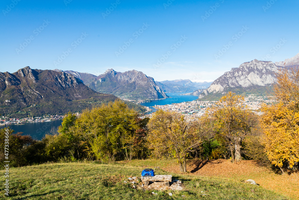 Aerial view of the city of Lecco, Italy, with the blue waters of Lake Como. Italian alps with blue sky on the background. Green meadow on the foreground.