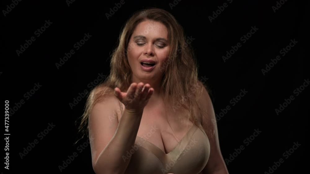 Seductive plus size woman gesturing air kiss looking at camera posing at black background. Portrait of self confident Caucasian obese lady with erotic facial expression. Temptation and passion concept Seductive plus size woman gesturing air kiss looking at camera posing at black background. Portrait of self confident Caucasian obese lady with erotic facial expression. Temptation and passion concept