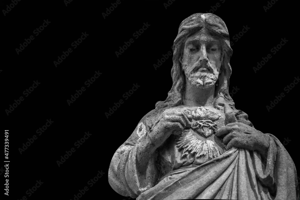 Antique stone statue of Jesus Christ pointing with fingers on his heart