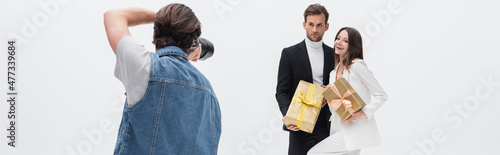 back view of photographer taking photo of stylish models with gift boxes isolated on white, banner.