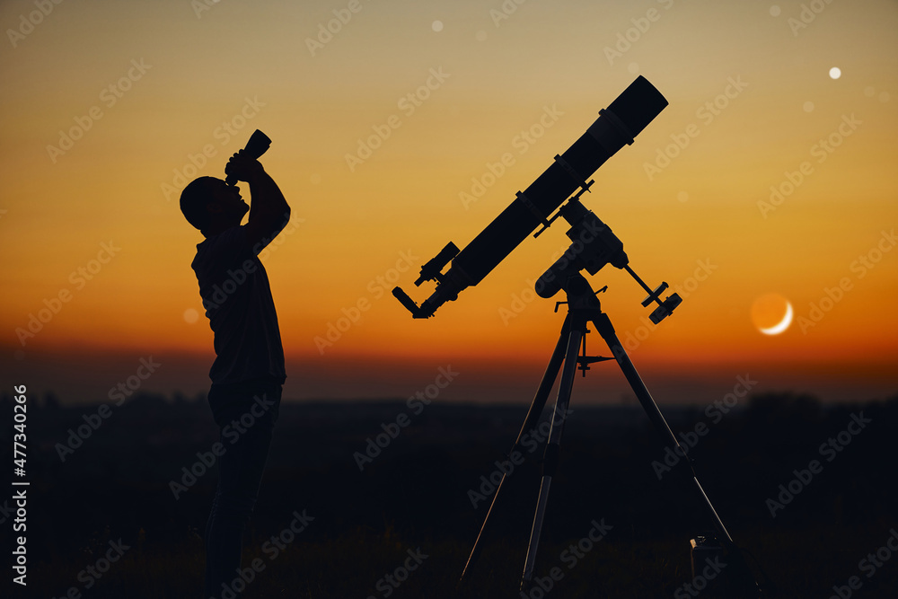 Silhouette of a man, telescope and countryside under the starry skies.