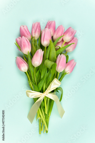 Fototapeta Naklejka Na Ścianę i Meble -  Bouquet of pink tulips with satin ribbon on a blue background. Mother's Day, Easter, Valentine's Day. Spring flowers. Vertical photo