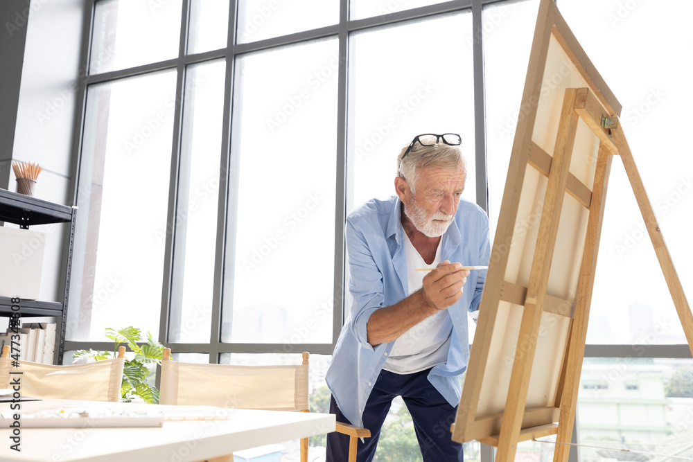 senior man painting a picture from paintbrush in free time senior man painting a picture from paintbrush in free time