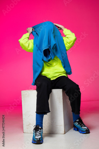 Young european boy with white skin isolated on pink taking off blue hoody