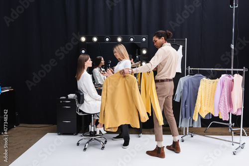 young makeup artist and african american stylist preparing professional model in photo studio. photo