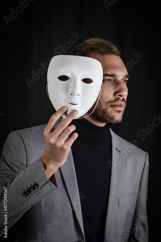 portrait of a serious young man holding a white mask in his hand, concept for being authentic and not showing a face of circumstance, but being truly