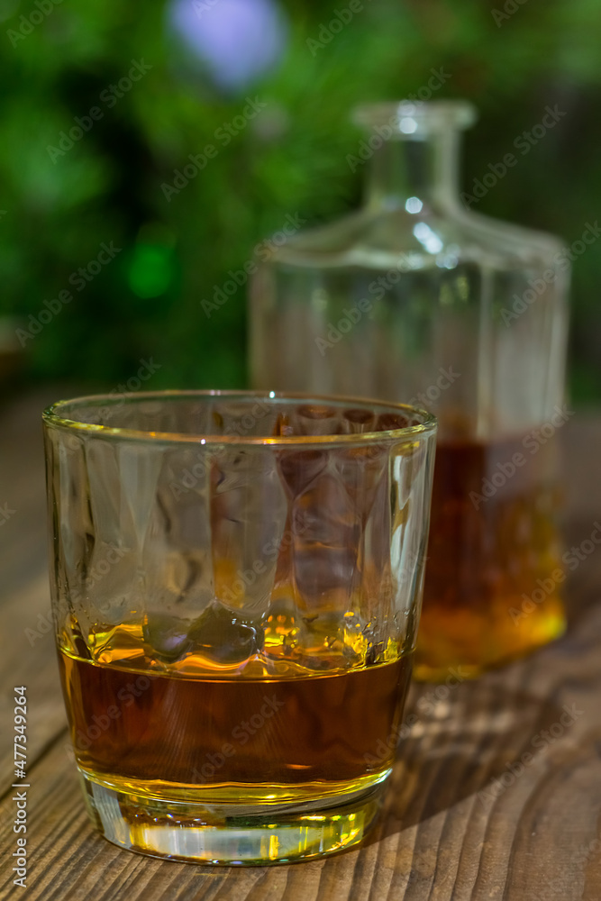 Vertical photo of a glass of whiskey on an old textured wooden table, against the background of a Christmas tree and bottle with alcohol in defocus Vertical photo of a glass of whiskey on an old textured wooden table, against the background of a Christmas tree and bottle with alcohol in defocus