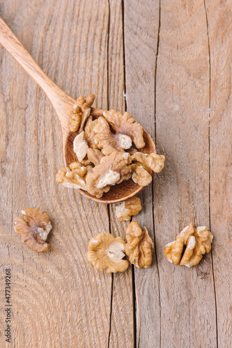 Peeled walnuts in spoon on wooden background