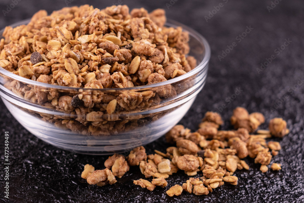 Healthy homemade muesli in a glass bowl on a black background.
Close-up. Healthy homemade muesli in a glass bowl on a black background.
Close-up.