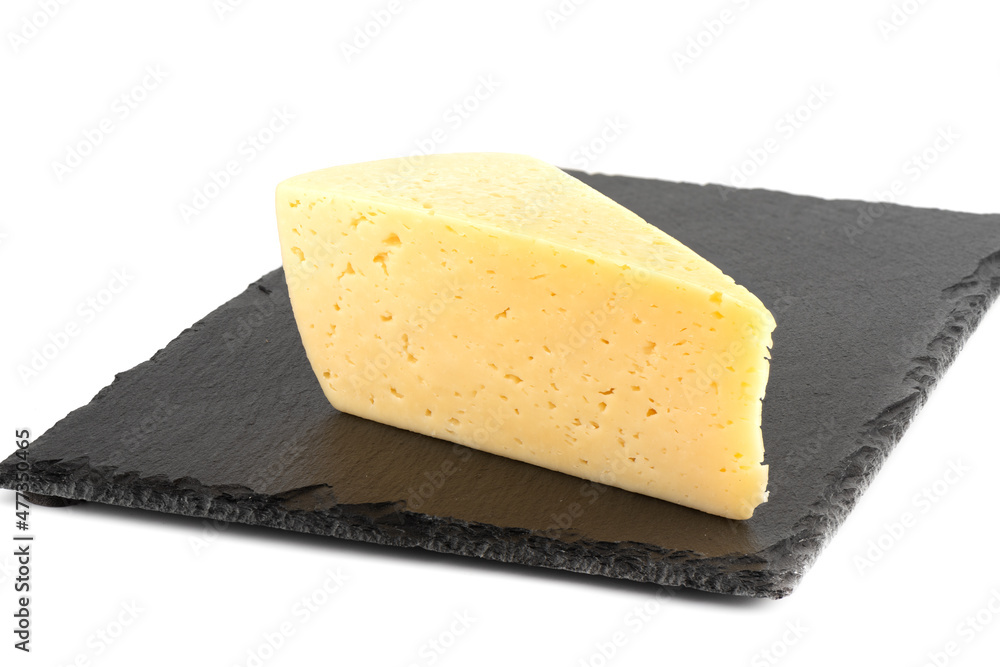 A piece of cheese on a stone cutting board over a white background.