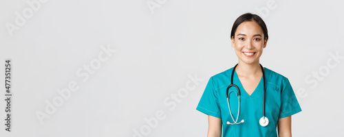 Healthcare workers, preventing virus, quarantine campaign concept. Close-up of smiling pleasant asian female nurse, physician in scrubs looking upbeat, listening to patient, white background photo