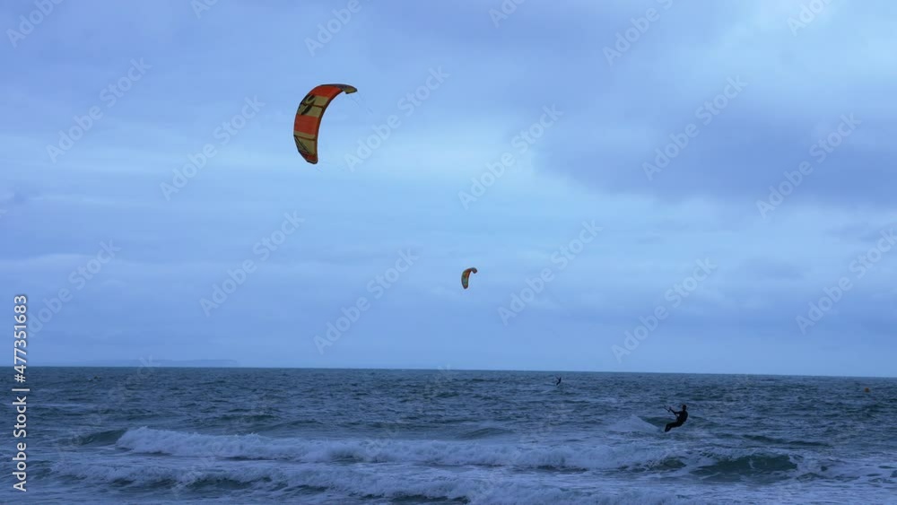 Kite surfer practising acrobatics in a Northern open ocean bay with emerald sea on a windy day near Old Harries rock cliffs.