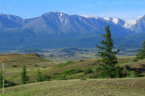 High mountain North-Chuisky range with glacier and snow-capped peaks and Kurai steppe, with hills and trees in summer