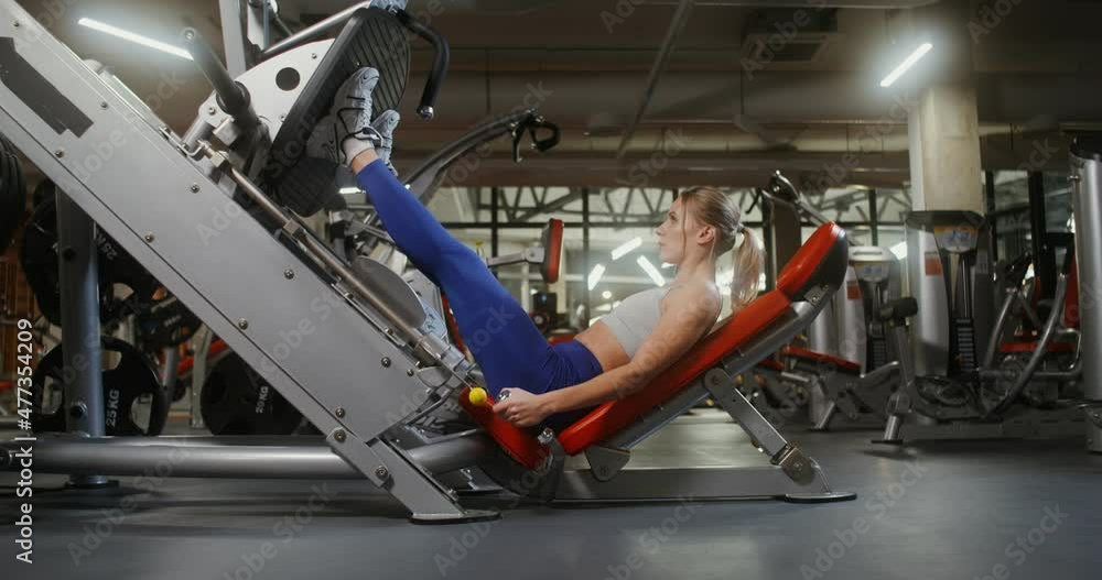 A woman doing exercises for the legs on the exercise machine A woman doing exercises for the legs on the exercise machine