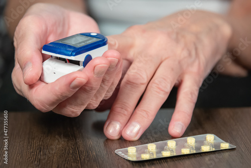 An older woman (old lady) takes a pulse and oxygen saturation measurement with a pulse oximeter. An elderly lady and her hands.