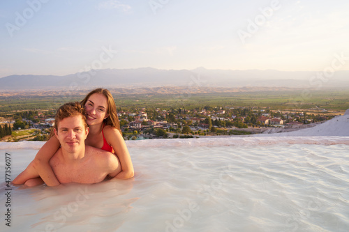 Loving couple at swimming pool in Pamukkale - St.Valentines Day concept.Lovers at sunset enjoing beautiful mountains view on their romantic journey. 