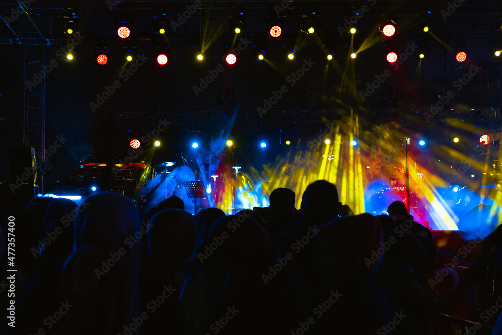 Concert background. Spotlights on the stage and silhouette of people in concert