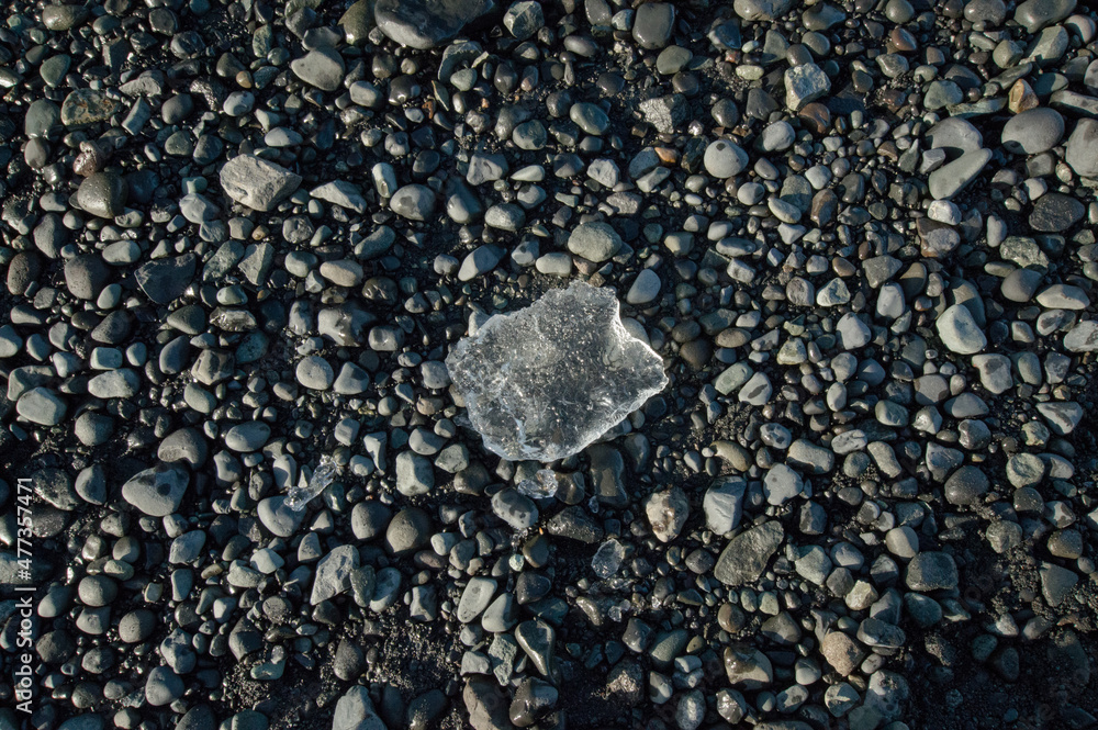 Opaque piece of ice from diamond beach, sitting on top of various sizes of grey and white pebbles Opaque piece of ice from diamond beach, sitting on top of various sizes of grey and white pebbles