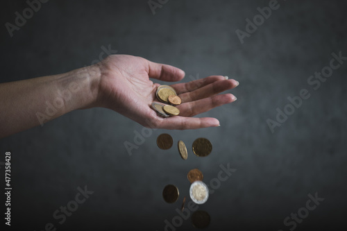 Concept of inflation. Woman hand hold an euro coins. Euro coins falling from woman hand. Declining value of money - Inflation.
