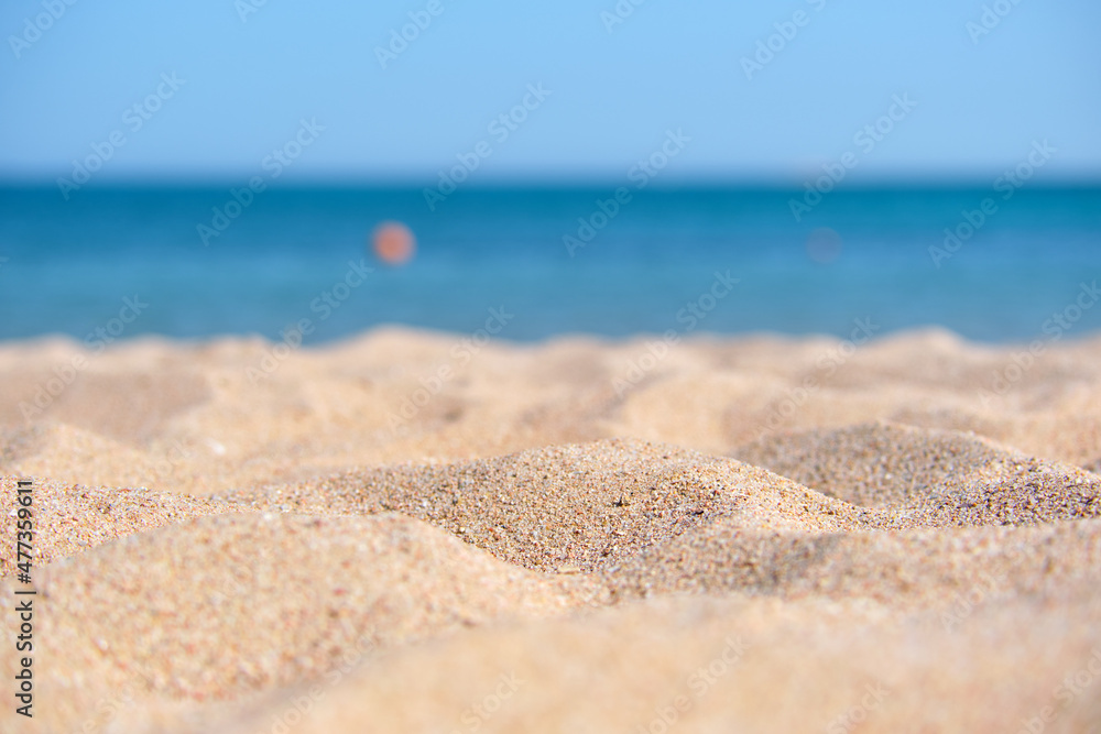 Close up of clean yellow sand surface covering seaside beach with blue sea water on background. Travel and vacations concept Close up of clean yellow sand surface covering seaside beach with blue sea water on background. Travel and vacations concept