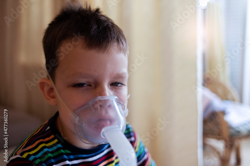 Cropped shot of a six year old boy making inhalation with nebulizer at home. Little boy in the inhalation mask with breathing troubles at home. Treatment of asthma.