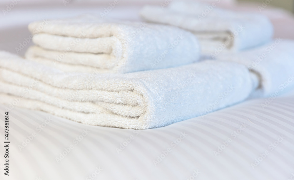 Fresh white towel on a hotel room bed, close up. Bedroom interior detail, comfort and hospitality Fresh white towel on a hotel room bed, close up. Bedroom interior detail, comfort and hospitality