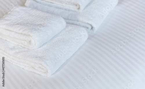 Fresh white towel on a hotel room bed, close up. Bedroom interior detail, comfort and hospitality