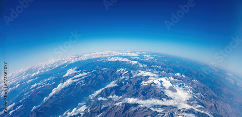 Fototapeta Naklejka Na Ścianę i Meble -  Curvature of planet earth. Aerial view. Blue sky over snowed mountain peaks. Space, science concept