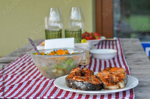 serving table with grilled fish, vegetable salad and vegetables on plates. selective focus macro shot with shallow DOF