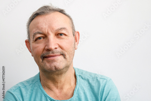 Portrait of a friendly elderly man with a mustache. A gray-haired man smiles looking at the camera