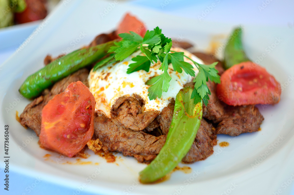 turkish doner kebab with yogurt and pepper tomatoes on white plate turkish doner kebab with yogurt and pepper tomatoes on white plate