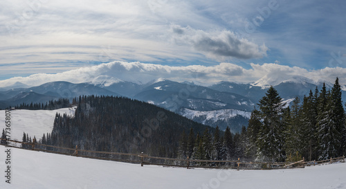 Winter remote alpine mountain village outskirts, countryside hills, groves and farmlands.