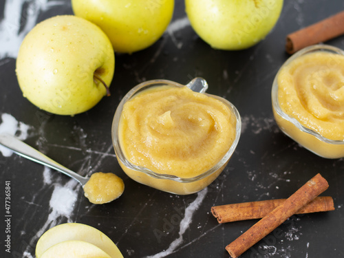 Canvas Print Homemade applesauce (apple puree or mousse) in small glass bowls with organic golden delicious apples and cinnamon sticks on a black textured table