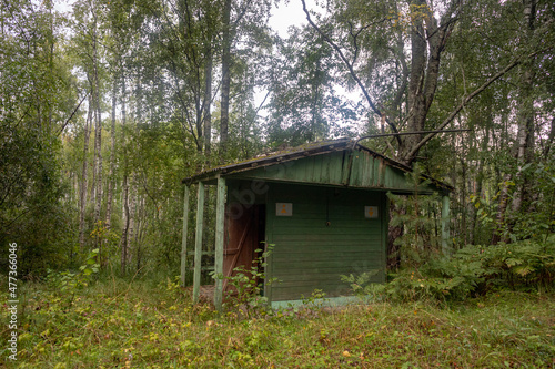 Abandoned wooden toilet of old times  rickety from time to time   grass and forest trees around