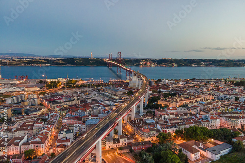 Aerial view of April 25th bridge with Christ the King statue (Cristo Rei) in background at sunset, view of Lisbon skyline at night, Alcântara, Lisbon, Portugal. photo