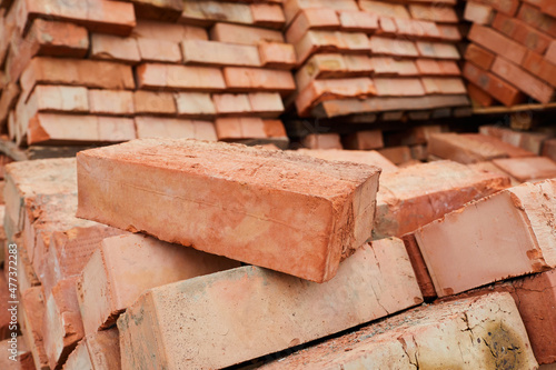 A stack of red clay bricks in rows close up. Lot of stacks of bricks on construction site photo