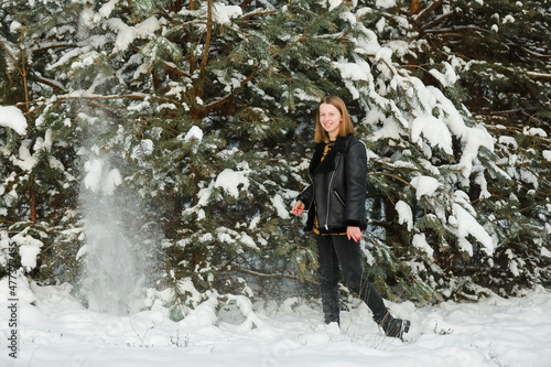 Young beautiful woman with short hair, in checkered shirt walking in snowy forest. winter holiday.