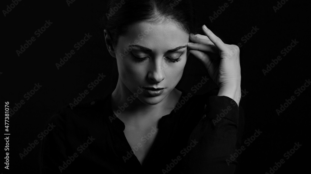 Business strong thinking woman find the answer in clever mind with closed eyes with fingers near the face  in black t-shirt on dark shadow black background. Closeup f
