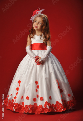 Little girl in a white dress on a red background..