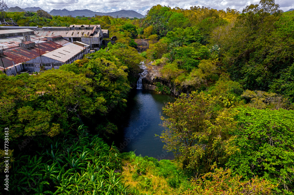 Aerial view of a waterfall hidden in a forest which is located near an old factory in Mauritius