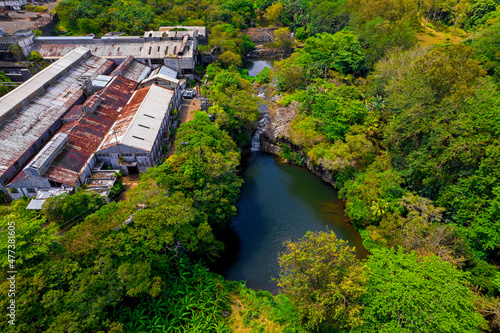 Aerial view of a waterfall hidden in a forest which is located near an old factory in Mauritius