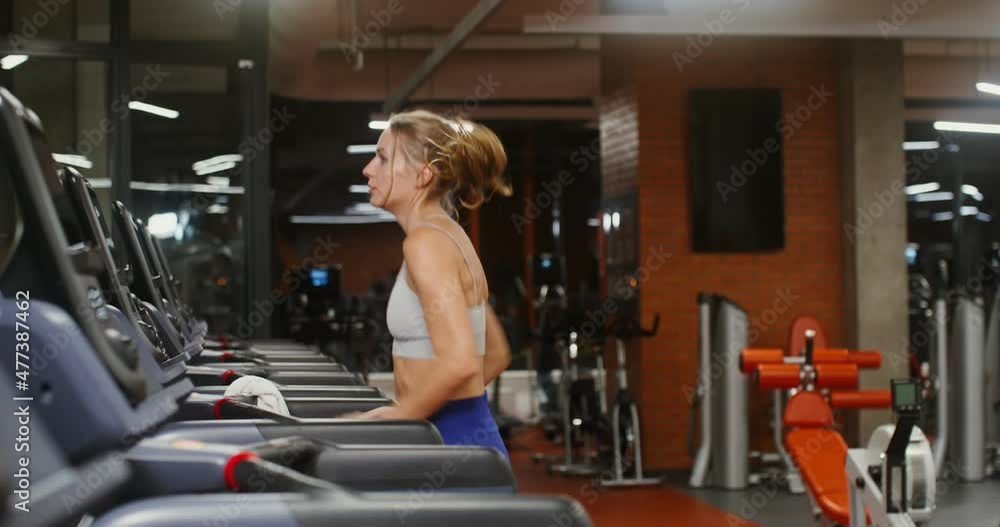 Young woman runs on a treadmill doing in the gym Young woman runs on a treadmill doing in the gym
