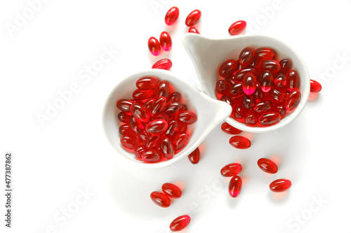 Foto Krill oil red gelatin capsules in white ceramic cups set on a white background